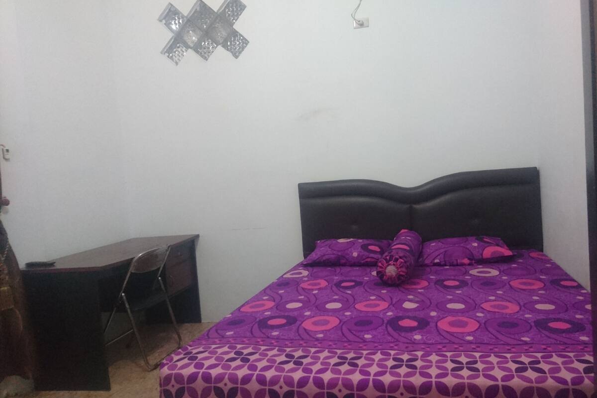Una habitación pequeña y poco amoblada con una cama, un escritorio y una silla.