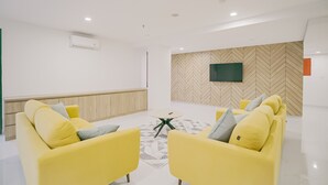 A modern waiting area with yellow sofas, a small round table, and a herringbone-patterned wall.