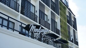 A multi-story building with a sign reading "Mendipong Mansion."