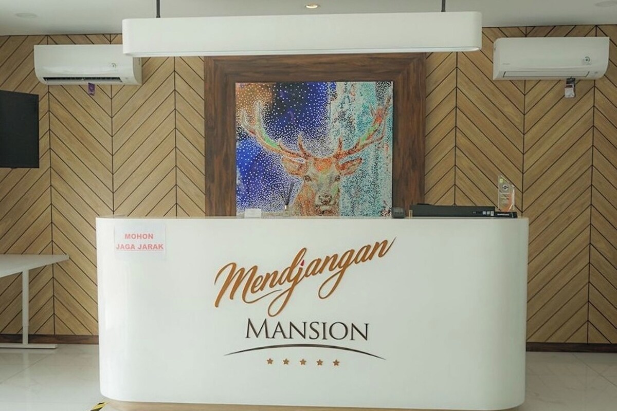 Un comptoir d’accueil orné d’une œuvre d’art encadrée représentant un cerf, avec l’inscription « Mendjangan Mansion ».