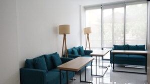 A modern living room with teal sofas, a wooden coffee table, and floor lamps.