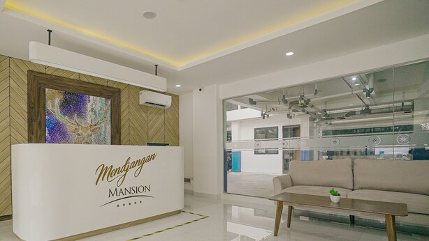 A reception area with a white reception desk labeled "Mendjargan MANSION," a sofa, and a coffee table.