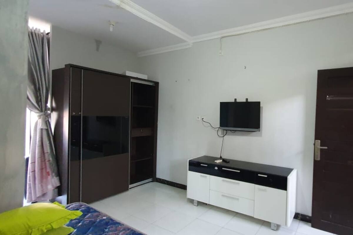 Un dormitorio con cama, armario, televisor y puerta.