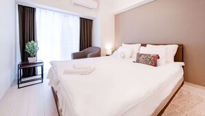 A hotel room with a large bed, a bedside table with a plant, a chair, and a window with curtains. - Sunshine Tower 202 (Tokyo)