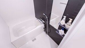 A modern bathroom with a white bathtub, a separate shower area, and a mirror above the sink. - Sunshine Tower 202 (Tokyo)