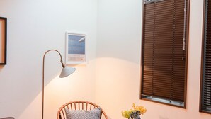 A cozy room with a brown leather sofa, a wicker chair, a small round table with a vase, and a framed picture on the wall. - Back to 90s American Style House (Tokyo)