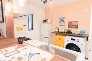 Ett modernt kök med diskho, spis, mikrovågsugn, kylskåp och tvättmaskin.