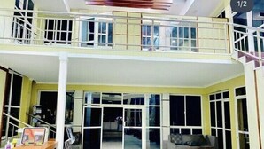 A two-story house with a balcony, large glass doors, and a seating area with a sofa and coffee table. - Royal Village Hotel Company (Dodoma)