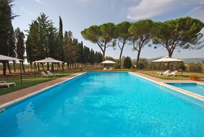 Una piscina al aire libre de temporada, sombrillas