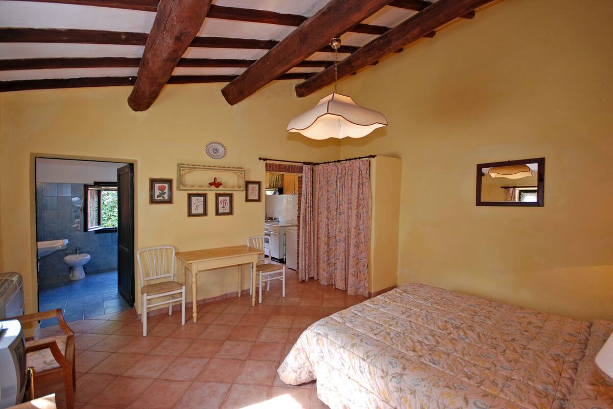 Ein Schlafzimmer mit Bett, Schreibtisch, Stuhl und einem durchgegangenen Tür sichtbaren Badezimmer.