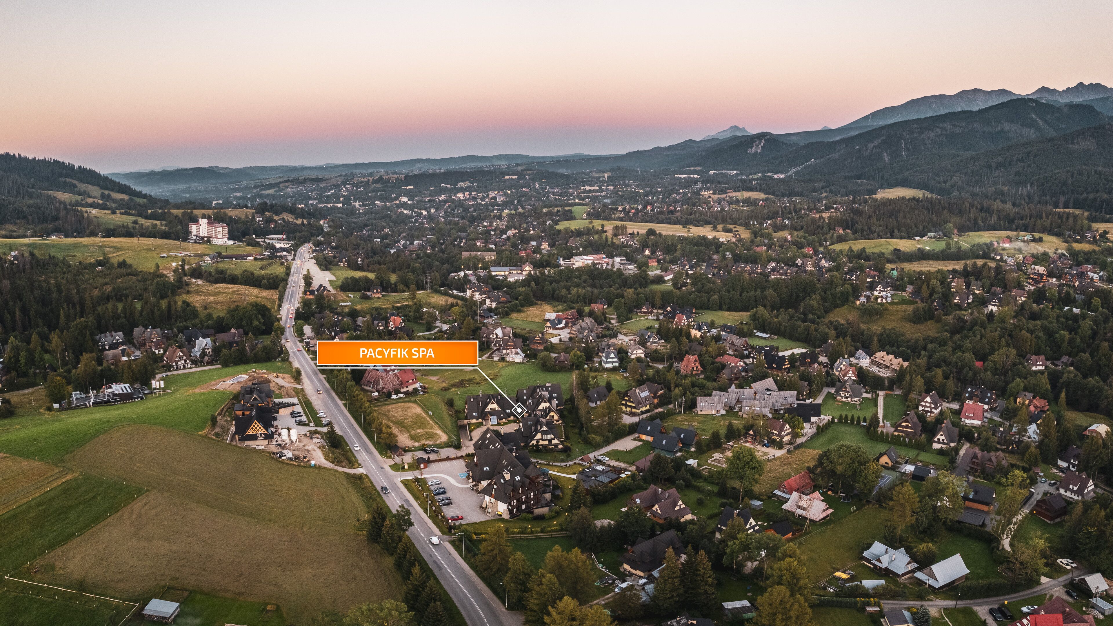 Ein Luftbild einer Stadt, durch die eine wichtige Straße führt, umgeben von Wohngebieten und Grünflächen.