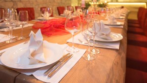 A restaurant with a long wooden table set for a meal, featuring white plates, silverware, and wine glasses. - Hotel Bären (Rupperswil)