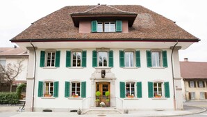 A two-story building with a symmetrical facade, green shutters, and a central entrance with a small porch. - Hotel Bären (Rupperswil)
