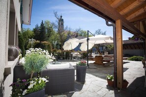 An outdoor patio area with wicker furniture, potted plants, and a large umbrella providing shade. - Hotel Bären (Rupperswil)