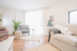 A cozy living room with a sofa, a chair, a small table, and a bookshelf.
