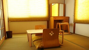 A traditional Japanese room with tatami flooring, a low table, a chair, and a cabinet with a mirror.