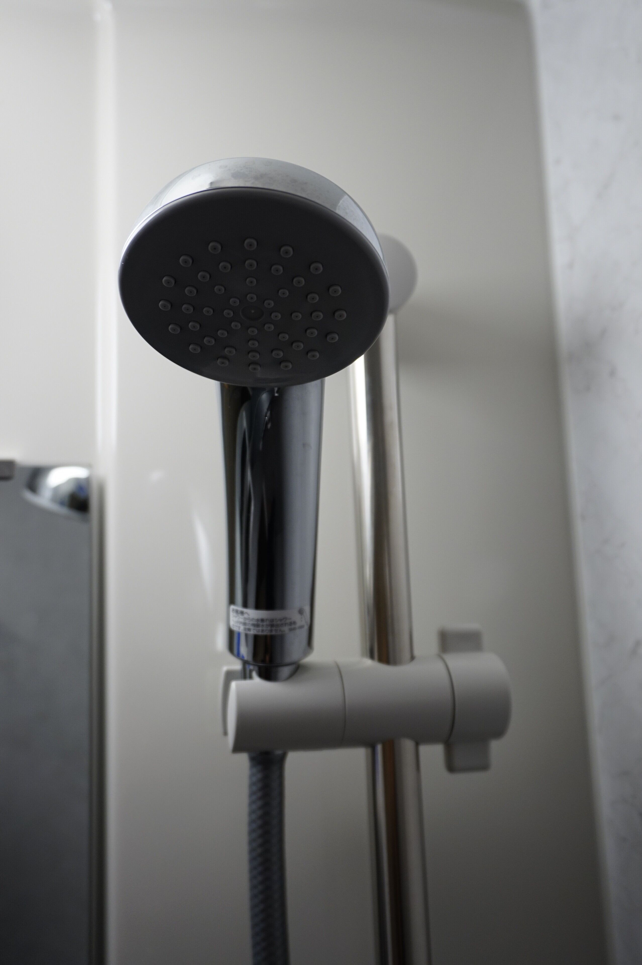Un cabezal de ducha moderno con efecto lluvia, unido a un grifo cromado y una manguera flexible.