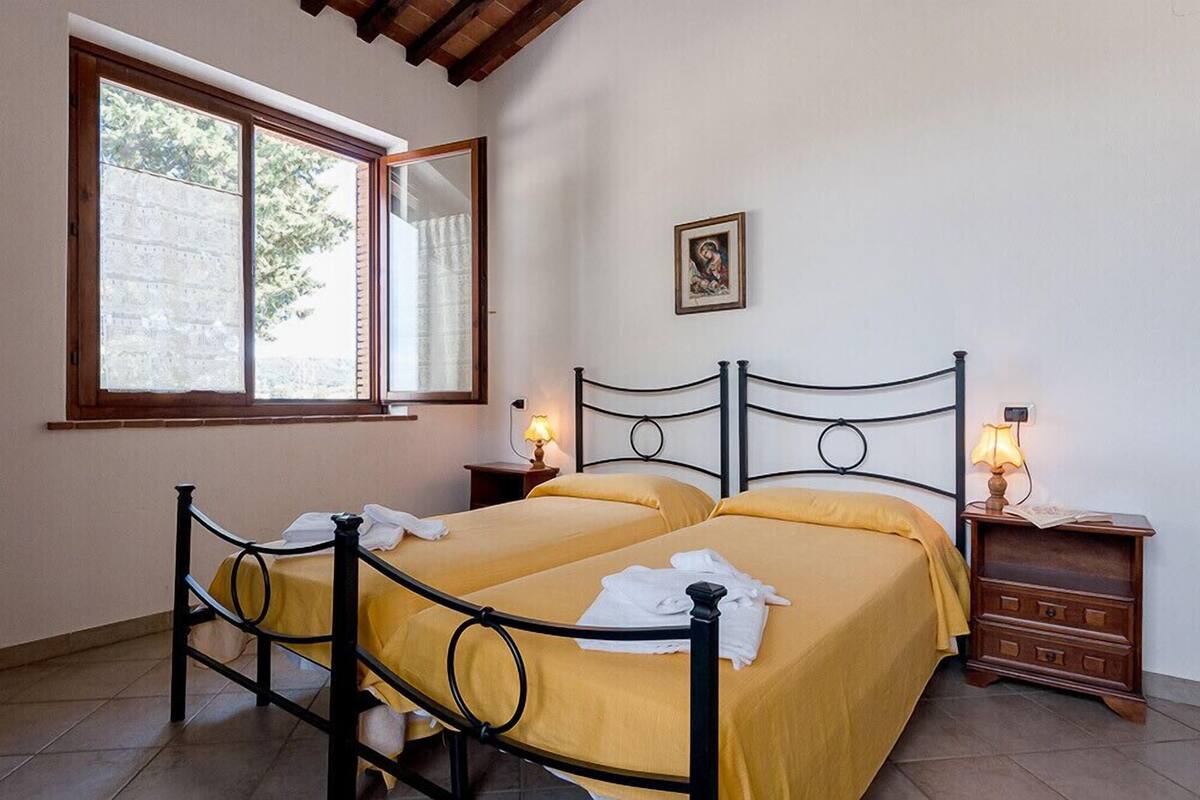 A room with two beds, a window, a picture on the wall, and bedside lamps.