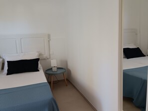 Une chambre d’hôtel avec deux lits, une petite table ronde et un miroir.