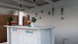 A room with a white bar area featuring fish decorations, a potted plant, and a shelf with decorative items. - Le Barchette 5 - piano terra (Lecce)