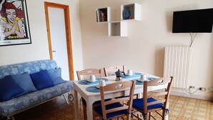 Ein Essbereich mit einem Tisch für zwei Personen, einem blauen Sofa und einem weißen Heizkörper.