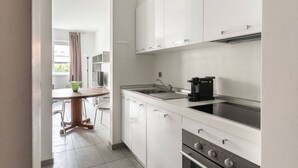 Une cuisine moderne avec des meubles blancs, une cuisinière et une machine à café.