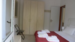 Una habitación de hotel con cama, armario, silla y mesa.