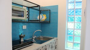 Una cocina con horno empotrado, lavamanos y ventana con vista a árboles.