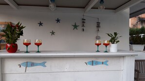 Una barra blanca con adornos de peces, plantas en macetas y decoraciones de estrellas de mar en la pared.