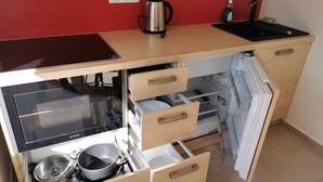 Una cocina compacta con horno integrado, un lavamanos y una cafetera.