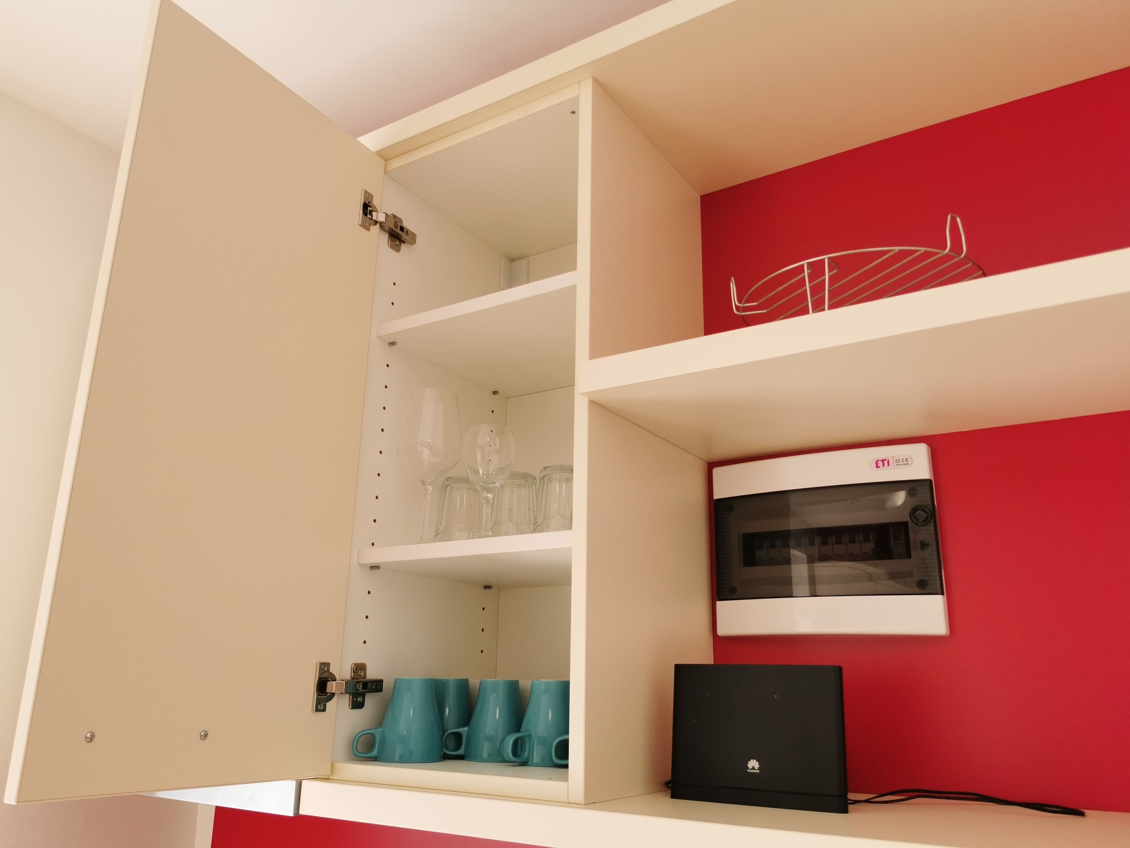 Une cuisine équipée d’un four à micro-ondes, d’un ordinateur portable et dont un des murs est peint en rouge.