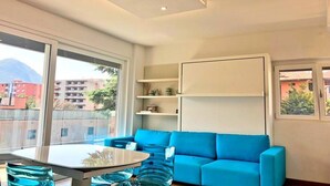 Un saló modern amb un sofà blau, una taula de centre de vidre i prestatges integrats.