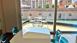 Una habitació moderna amb un finestral gran, una taula rodona i dues cadires.