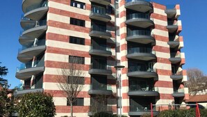 A multi-story residential building with a distinctive striped facade, balconies, and a clear sky.