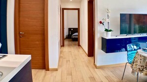 A hallway with wooden doors, a dining area with a table and chairs, and a TV on a stand.