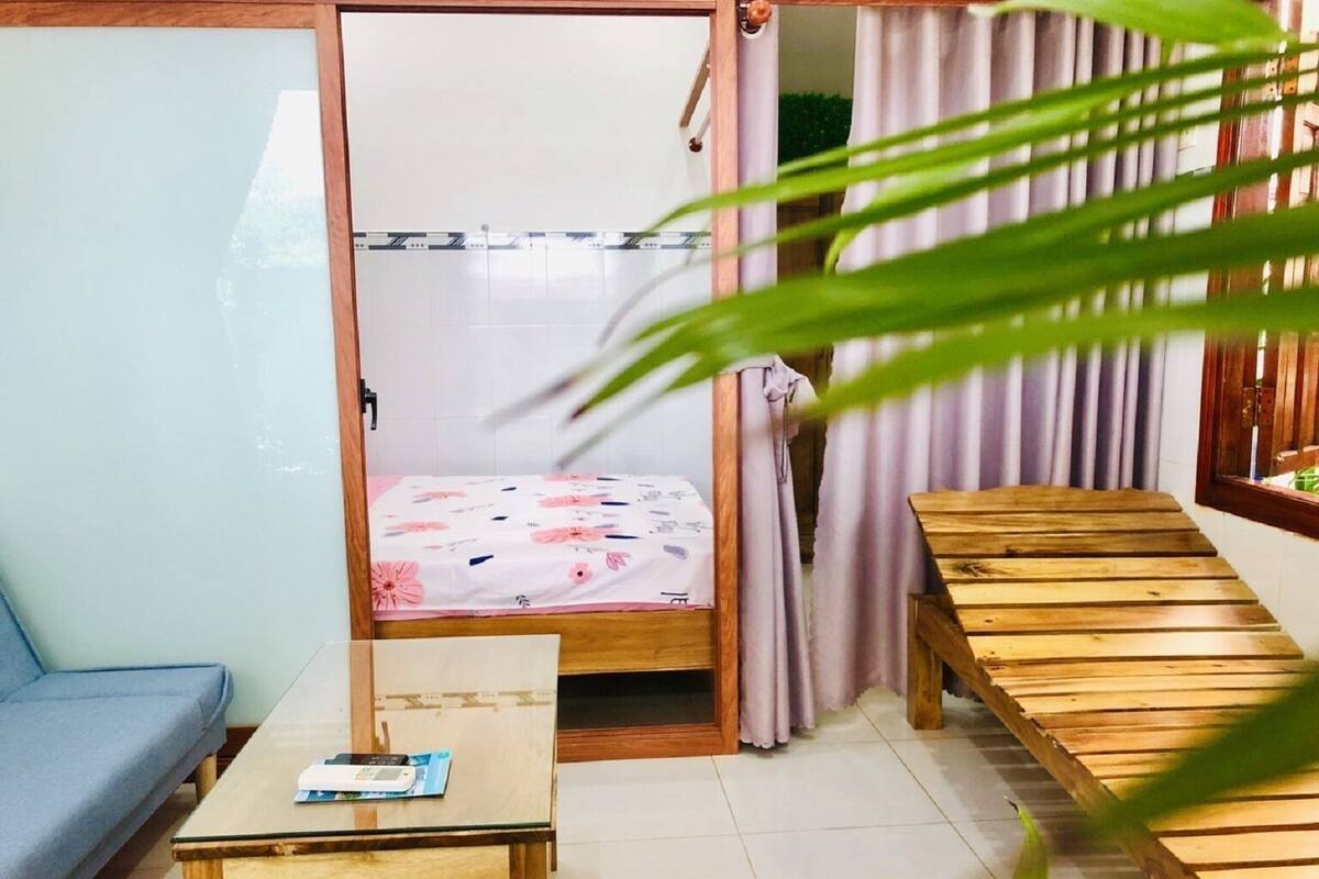 A room with a bed, a small table, a sofa, and a wooden bench.