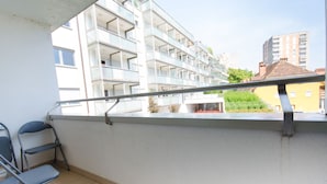 A balcony with a metal railing, a white wall, and a view of a multi-story building with balconies. - City centre studio with a balcony (Ljubljana)