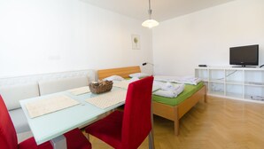A room with a bed, a desk, a chair, a television, and a shelf. - City centre studio with a balcony (Ljubljana)