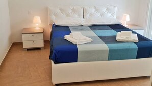 A neatly made bed with a quilt, two bedside lamps, and a small bedside table with a lamp.