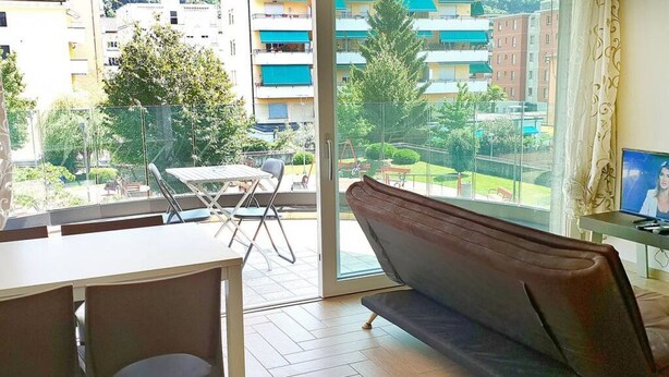 A balcony with a dining table and chairs, a sofa, and a TV.