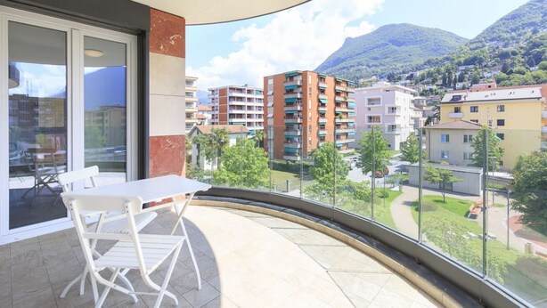 Ein Balkon mit Tisch und Stühlen mit Blick auf ein Wohngebiet, Gebäude und einen Berg.