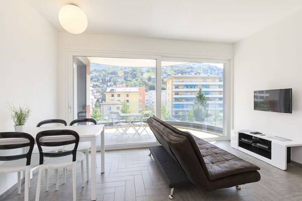 Een moderne woonkamer met een bank, eettafel, stoelen en een televisie.
