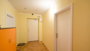Ein Flur mit Holzdielen im Fischgrätmuster, einer weißen Tür und einem orangefarbenen Schrank.