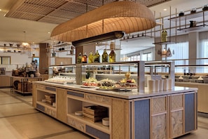 A buffet area with a variety of food items and a large woven overhead light fixture. - Mare Paphos (Kissonerga)