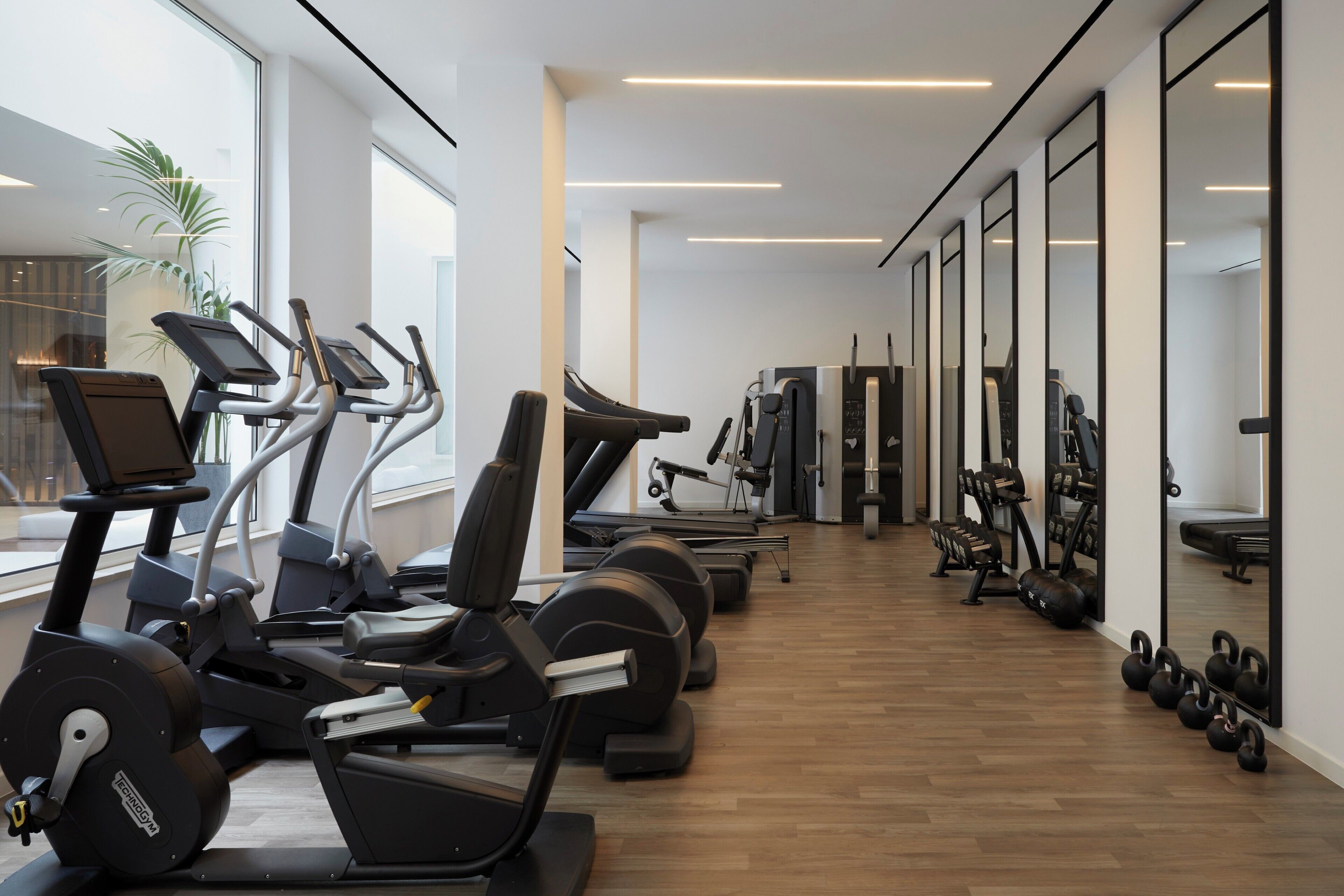 Un gimnasio con cintas de correr, elípticas y pesas libres.