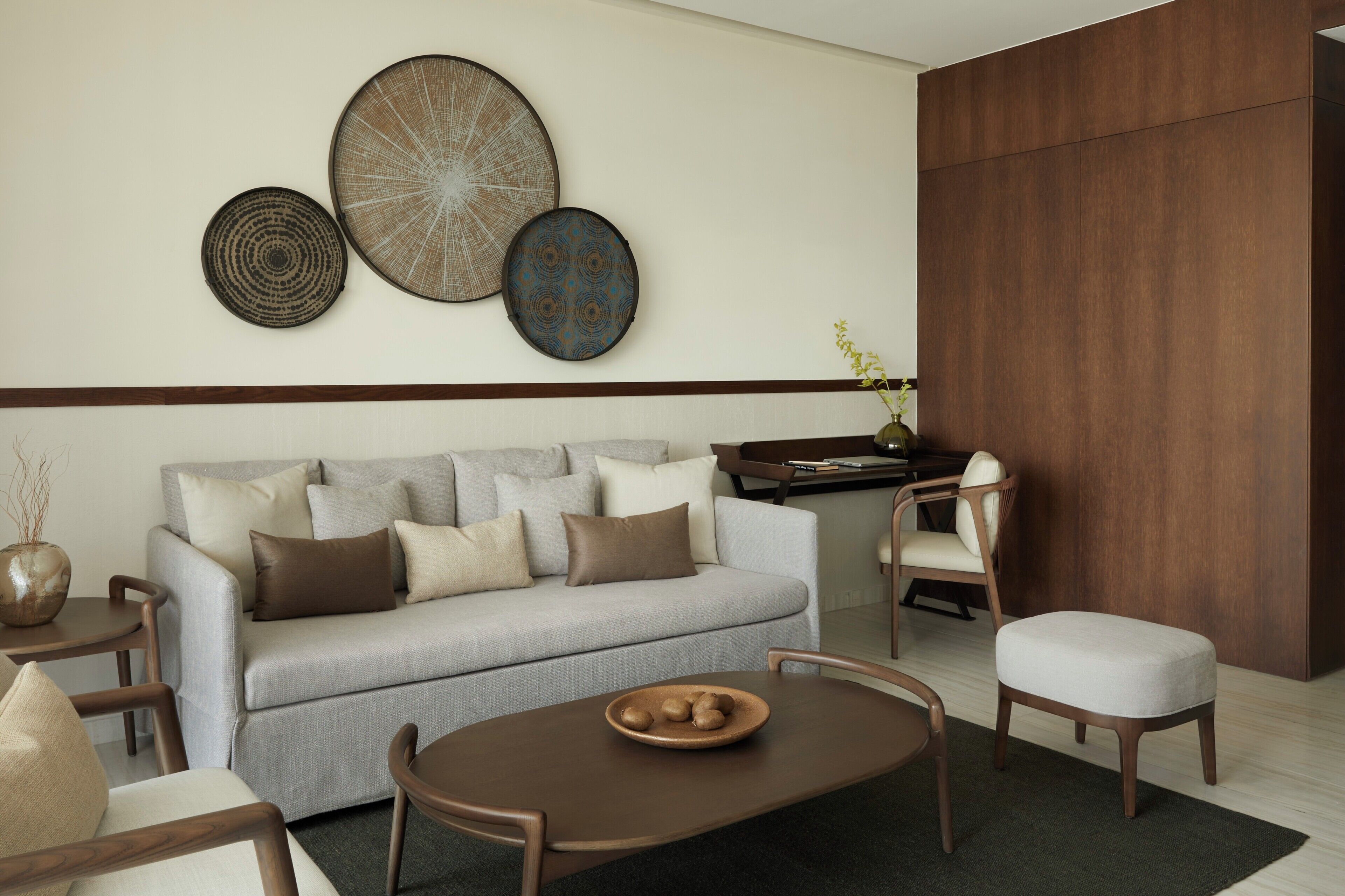 A modern living room with a grey sofa, wooden coffee table, and a dining area with a wooden table and chairs.