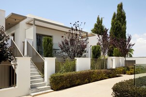Una casa moderna de dos pisos con escaleras, un porche cubierto y un jardín bien cuidado.