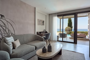 A modern living room with a grey sofa, a coffee table, and a view of the sea through large sliding doors. - Mare Paphos (Kissonerga)