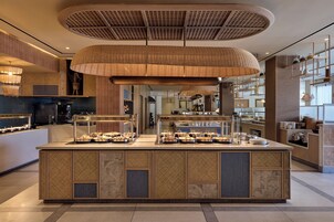 Un'area buffet con un'isola centrale, lampade intrecciate a soffitto e una cucina moderna sullo sfondo.