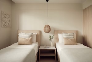 Una habitación de hotel con dos camas, una mesita de noche con lámpara y un adorno en la pared.